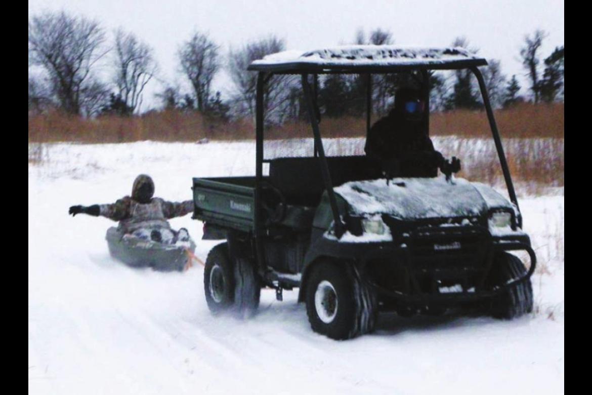 A CHOCTAW COUNTY man uses a Kawasaki Mule to pull a teenager in a kayak across a snowcovered pasture near Soper during the recent winter storm.