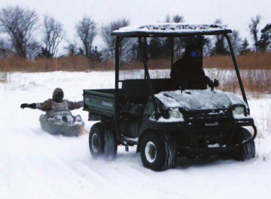 A CHOCTAW COUNTY man uses a Kawasaki Mule to pull a teenager in a kayak across a snowcovered pasture near Soper during the recent winter storm.