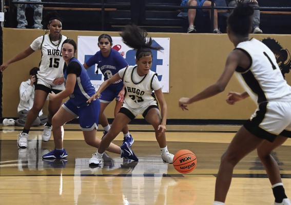 JALYN JOHNSON throws on the brakes to gather up a loose ball for the Hugo Lady Buffaloes in action against the Hartshorne Lady Miners during play at the Hugo Festival. Checking up to assist Johnson is teammate Sa’Rya Smith. (Below) ADDIE WATTS doesn’t waste any time putting defensive pressure on a Hartshorne player, pinning her inches inside the base line as the official watches the play. Hugo News Phots / Stan Stamper