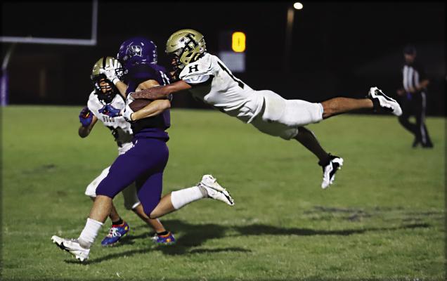 HUGO SENIOR LaMARCUS DAVIS didn’t have his red cape on Friday night but he played the role of Superman in the Buffaloes’ big road win over Wilburton, 18-14. Above, Davis makes a flying tackle on a Wilburton ball carrier as teammate Travion King comes in to assist. Davis also stepped in to play quarterback for Hugo in the second half when starter Jayka Santillan was sidelined by an injury. Hugo News Photo / Kelli Stacy