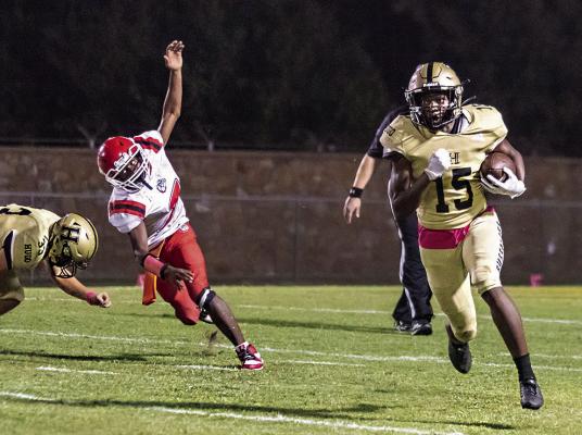 HUGO’s CECIL SMITH tucks the football under his arm and sets sail into the open field Friday as the Buffaloes put a sound 45-6 whipping on the Okmulgee Bulldogs. Throwing a key block to help Smith gain more yards on the play was teammate Zakk Gilmore. (Below) Ja’Mari Scroggins runs for a big gain into the center of Buff Parker Field as teammate Casen Knight hustles to get into position to make a block. Hugo News Photos / Bobby Hamill
