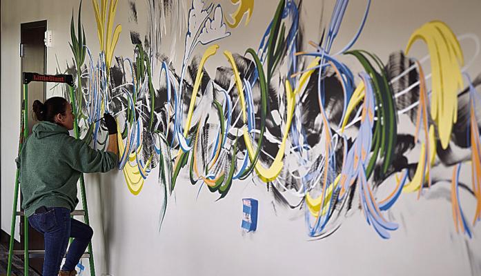 Rhiana Deck, muralist, actively worked on the mural in the front hallway of the clinic expansion during the ribbon cutting.