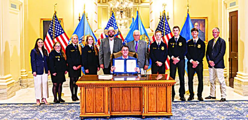 Gov. Kevin Stitt, Sen. Roland Pederson (center right) and Rep. Dillon Travis (center left) are flanked by Burlington FFA Adviser Addison Jenlink, FFA students Kyden Archuleta, Cash Dotson, Remington Farney, Morgan Matzke, Maddox Morgan, Rylee Sims and Keeff Felty, former National Association of Wheat Growers president, at a ceremonial bill signing on Tuesday, Aug. 11 at the Oklahoma state Capitol in Oklahoma City.