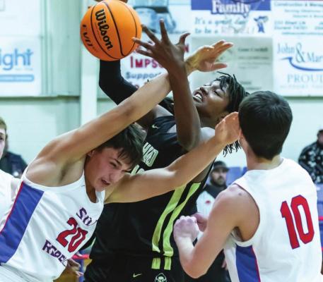 DAWSON BOSTIC (above) battles with two Silo Rebel players for control of a rebound during recent play at Silo. Bostic came out with the ball and booked 12 points to contribute to the Buffaloes’ 62-45 victory.