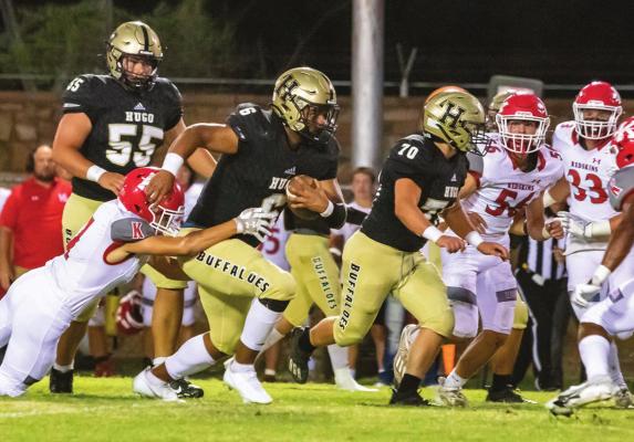 HERE COMES THE BUS...! HUGO’S ADEN PARISH drags a Kingston defender with him through the offensive line hole during last Friday’s clash at Gene Nesbit Stadium in Hugo. Looking for a block in front of Parish is teammate Trandon Morgan. Hugo News Photo / Bobby Hamill