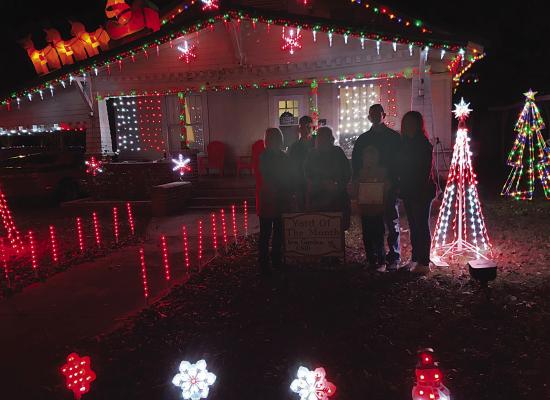 The Iris Garden Club Christmas Yard of the Month was Mr. and Mrs. Justin Johnson at 408 E. Duke. Pictured are the Johnsons and their son with club members: Rick and Holley Lowrance and Harolynn Wofford. They received an Ace gift card for their efforts.