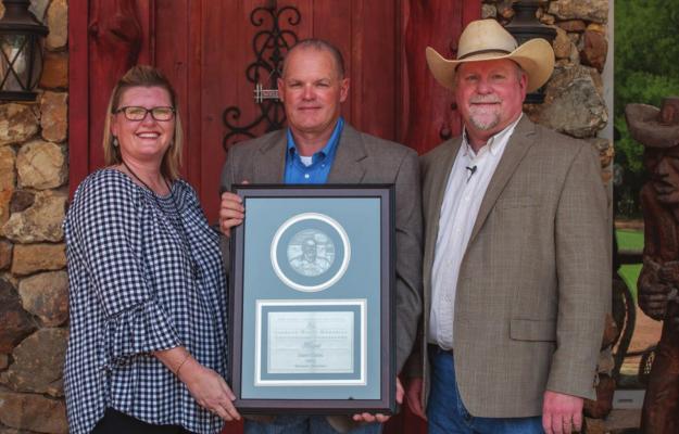 RUSTY DANIEL (center) received the 2020 Leonard Wyatt Memorial Outstanding Cooperator Award. Pictured with him are his wife Stephanie (left), and planned consultation manager and senior soils and crops consultant James Locke.