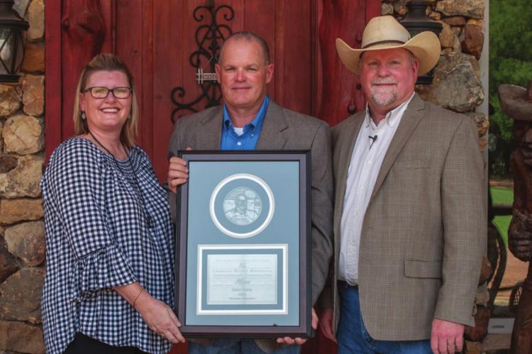 RUSTY DANIEL (center) received the 2020 Leonard Wyatt Memorial Outstanding Cooperator Award. Pictured with him are his wife Stephanie (left), and planned consultation manager and senior soils and crops consultant James Locke.