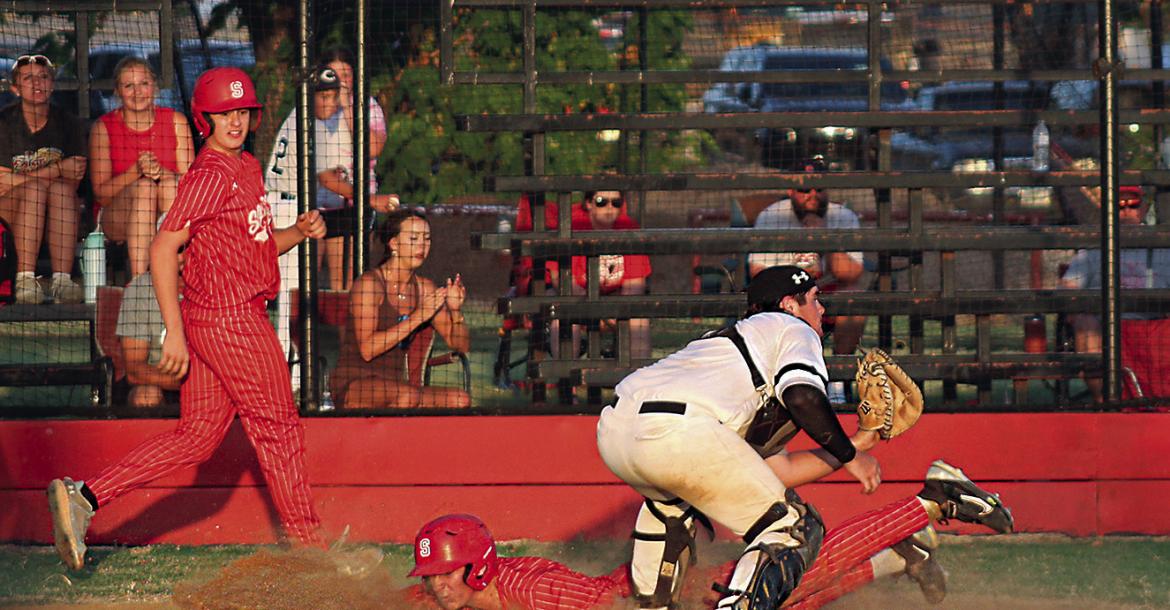 SOPER’S LEVI BAILEY SCORES and watches as teammate Dallin Gilbert slides safely in to home plate ahead of the throw for two big runs for the Soper Red Bears in recent baseball action. Brian Moore Photo